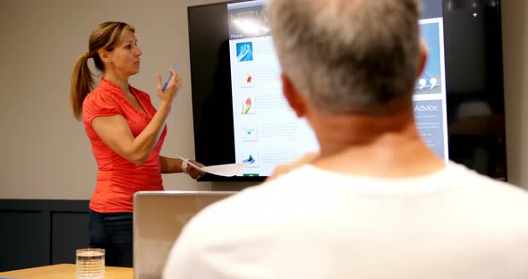 Executives discussing over lcd screen in conference room