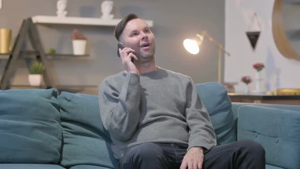 Casual Man Talking on Smartphone on Sofa