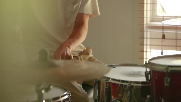 Drummer practicing rudiments on personal drum kit with foreground gradient and soft natural light en
