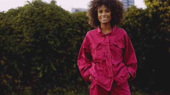 Smiling Young Woman With Afro Hair In Bright Pink Fashion