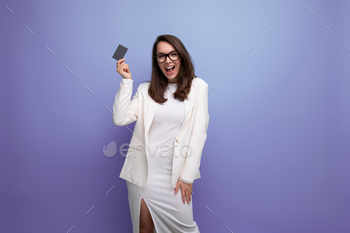 portrait of a young woman with dark hair in a white dress holding a money card for shopping