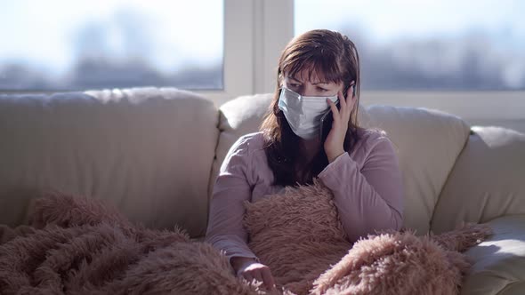 Worried Woman in Medical Mask Talking on the Phone