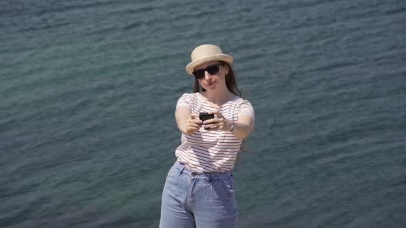 A Woman Takes a Selfie on the Background of the Sea