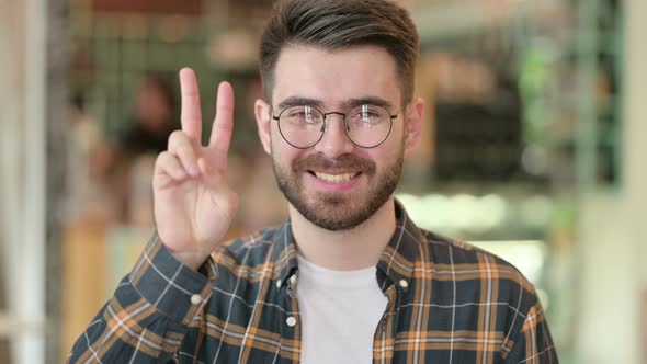 Portrait of Young Man Showing Victory Sign with Hand 