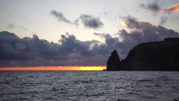 Colorful Warm Sunset Over the Sea and Volcanic Basalt Rocks Like in Iceland