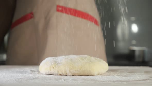 Pastry Chef Sprinkles Dough with Flour on the Table