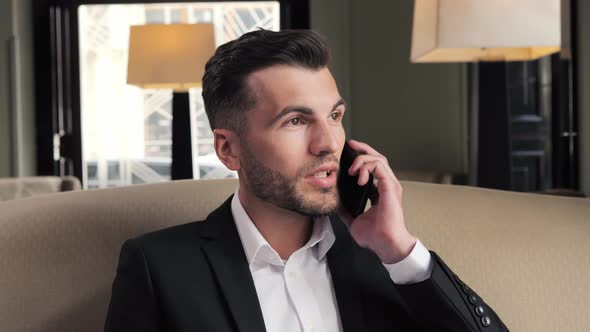 Portrait of Handsome Stylish Man Having Phone Talk in Hotel Lobby