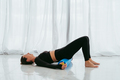 Woman with foam roller on floor for body tension support during yoga class. - PhotoDune Item for Sale