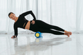 Woman doing stretching warming up pilates exercises using foam roller at home. - PhotoDune Item for Sale