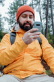 Bearded man in hat using mobile phone. Guy looking at mobile and smiling - PhotoDune Item for Sale