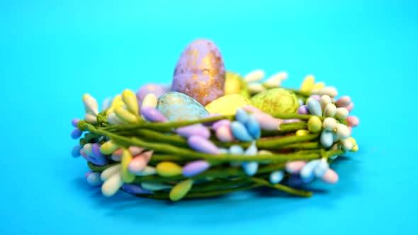 Handheld shot of colorful easter eggs kept in a flower nest in a blue background.