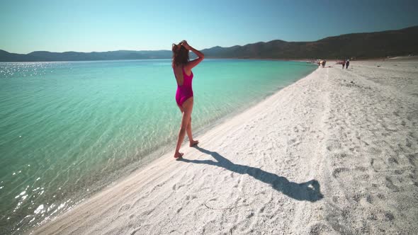 Sexy Female Model in Pink Swimsuit Walking on the White Beach of the Clear Tropical Turquoise Sea