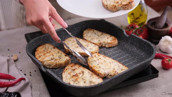 Woman Putting Toasted Bread From Grill Frying Pan Onto White Ceramic Plate