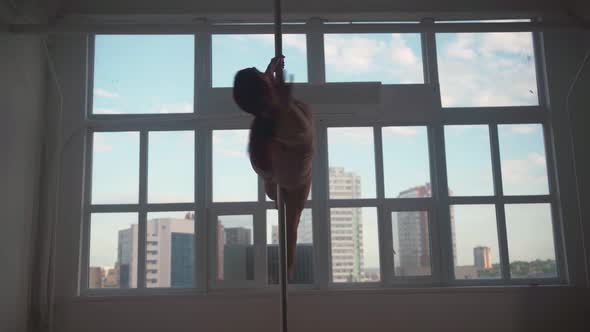 Athletic Woman Pole Dancer Performs Spectacular Tricks on Pole