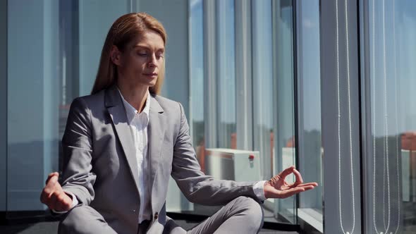 Calm Tired Business Woman Dressed in Classic Suit Meditate in Lotus Position