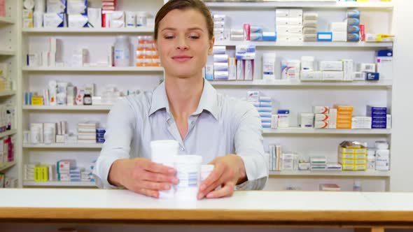 Smiling pharmacist holding medicine container in pharmacy