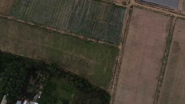 Aerial top down shot of Cu Chi, Vietnam with greenhouse farm houses, forests on sunny day with blue