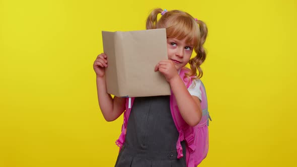 Funny Kid Primary School Girl with Ponytails Wearing Uniform Peeping While Hiding Behind a Book