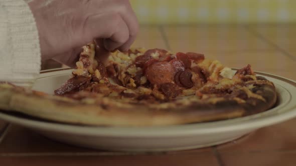 Hand grabbing slice of pepperoni pizza  close up shot