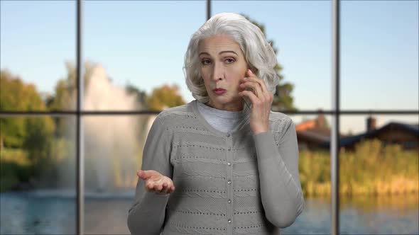 Mature Woman Talking on Glass Phone.