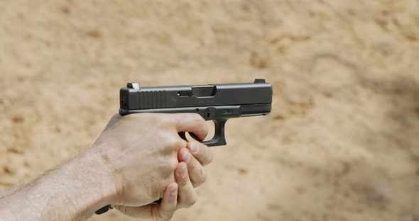 Slow motion of a hand gun firing in a firing range with cartridge flying away