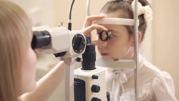 Female Eye Doctor Inspecting Little Girl in Office Using Biomicroscopy Method