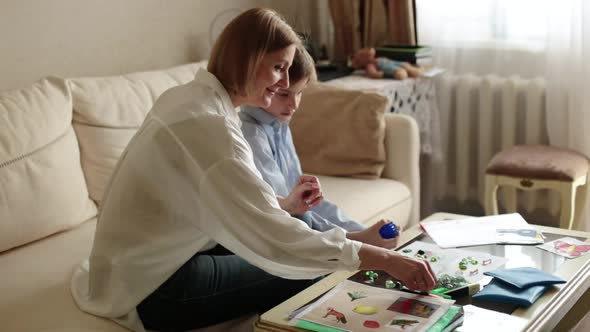 Adult Woman and a Teenager are Sitting Behind on the Couch Playing a Board Game