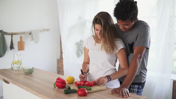 Handsome African Guy is Embracing Caucasian Girlfriend While Helping Her to Prepare Food in the