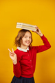 Portrait of happy teenage schoolgirl in uniform holding books on head - PhotoDune Item for Sale