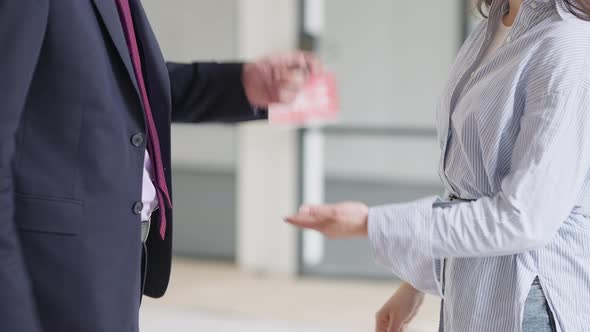 Side View of Unrecognizable Seller and Buyer Shaking Hands and Passing Key Indoors