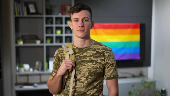 Portrait of Confident Young Man in Camouflage Tshirt Looking at Camera with Rainbow LGBTQ Flag at