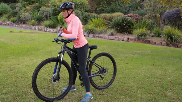 Female cyclist drinking water in park