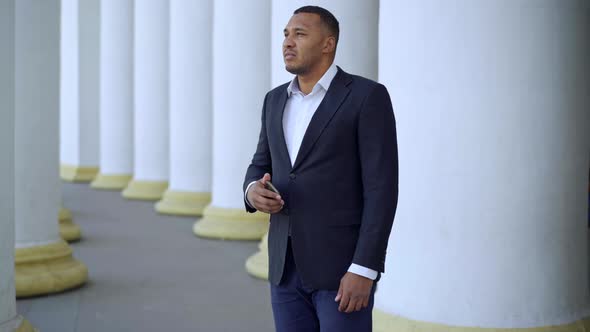 Portrait of Handsome Thoughtful African American Man in Formal Business Suit Standing at White