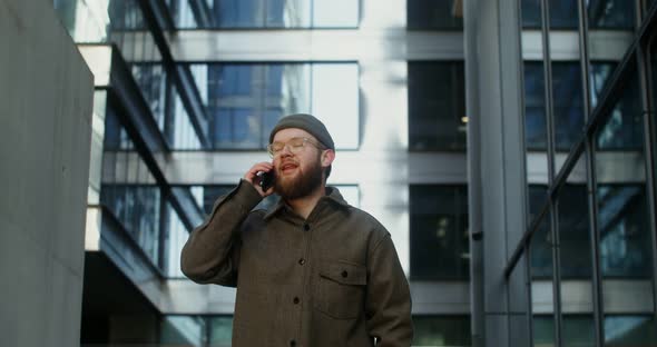 A Young Man is Typing on a Mobile Phone While Walking Around the Business Center