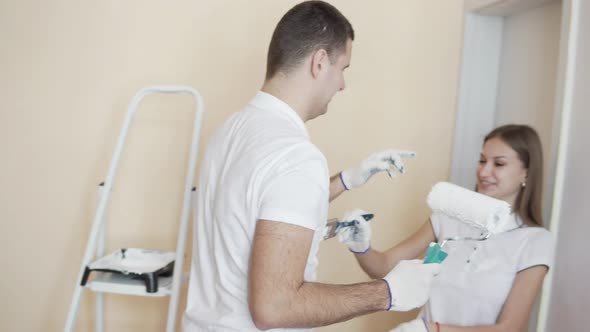 Beautiful Young Couple Painting the Walls and Each Other in a New Apartment Laughing and Having Fun