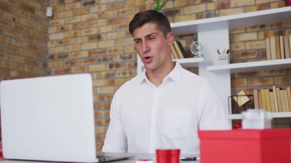 Caucasian man making video call using laptop making love heart shape and talking