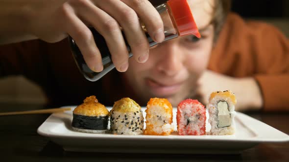 Man Pours Soy Sauce on Delicious Sushi of Different Types