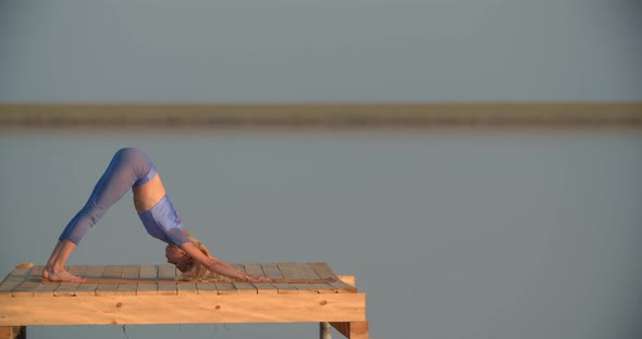 Sports and Recreation Young Lady is Stretching and Doing Yoga on a Platform