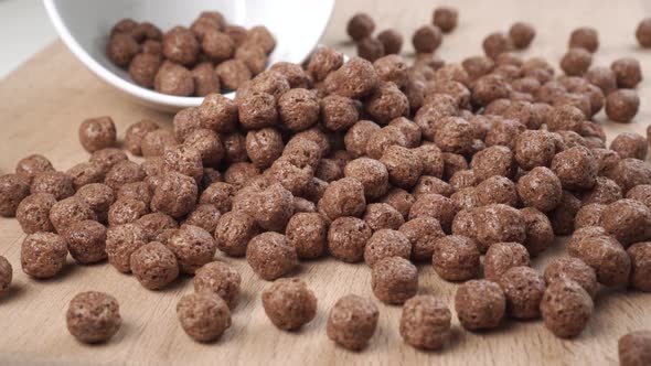 Crispy chocolate cereal flakes scattered on a wooden cutting kitchen board