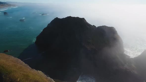 AERIAL: View from far above flying over some very large rock formations sitting on Oregon's coastlin