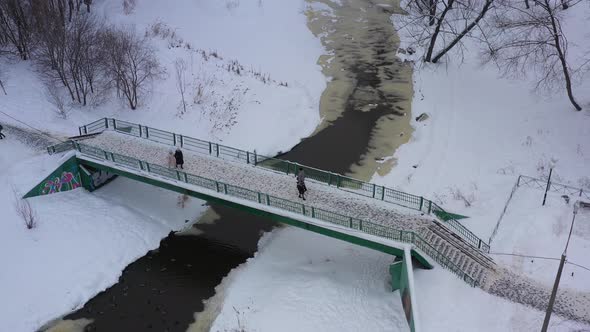 The City's Pedestrian Bridge People Walk Across the Bridge Over the River in Winter