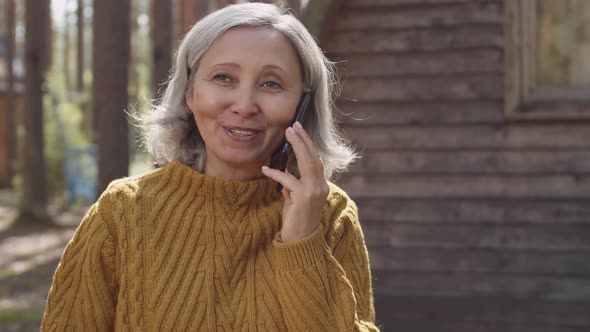 Aged Woman Talking on Phone in Tourist Camp