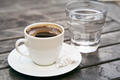Small cap of strong coffee espresso with glass of clean water on wooden table. - PhotoDune Item for Sale