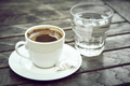 Small cap of strong coffee espresso with glass of clean water on wooden table. - PhotoDune Item for Sale
