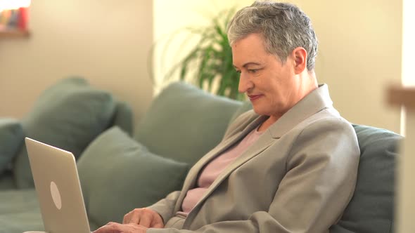 Happy Old Senior Woman Grandmother Using Laptop Computer at Home