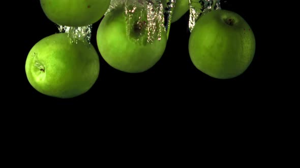 Super Slow Motion Green Apples Fall Under the Water with Air Bubbles