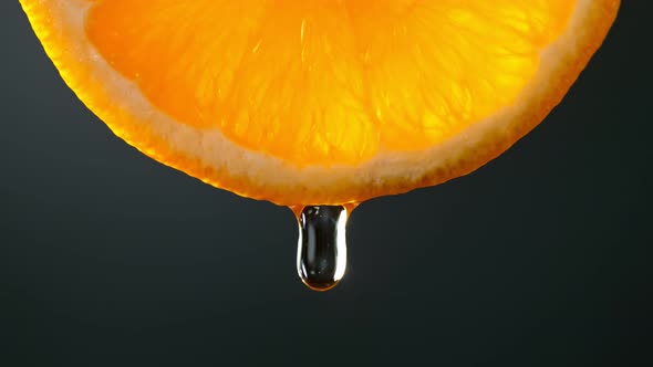 Super Slow Motion Macro Shot of Water Drop Falling From Fresh Orange Slice on Black at 1000Fps