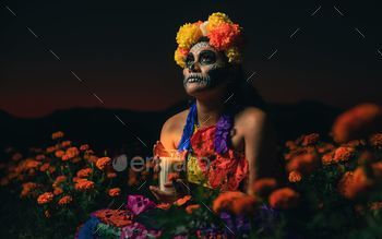 A beautiful female in traditional dress and makeup posing for the Day of the Dead on a floral field
