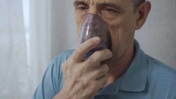 Closeup Portrait of an Elderly Man Making Inhalation