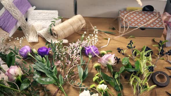 View From Above Wooden Table with Flowers Scissors Tapes Decorating Paper and Other Tools for